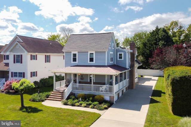 view of front of home featuring a front yard, driveway, a chimney, and covered porch