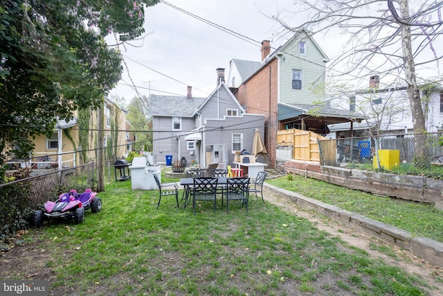 back of house with a yard, a chimney, and a fenced backyard