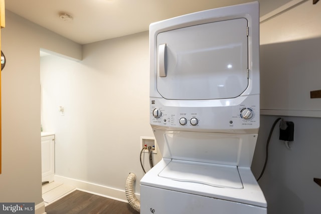 washroom with stacked washer and clothes dryer, dark wood finished floors, baseboards, and laundry area
