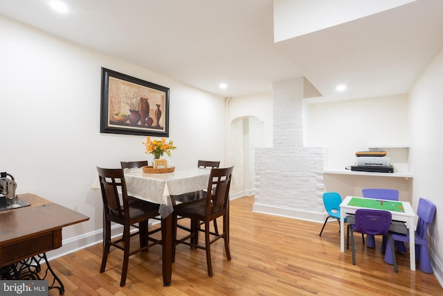 dining space with arched walkways, wood finished floors, baseboards, and recessed lighting
