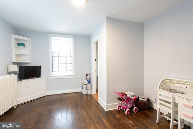 recreation room with radiator, wood finished floors, and baseboards