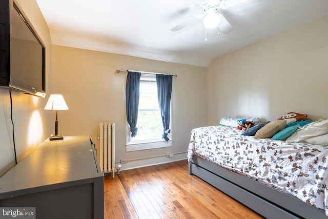 bedroom with radiator, light wood finished floors, baseboards, and a ceiling fan