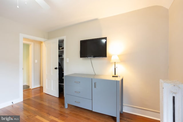 bedroom with radiator heating unit, baseboards, and wood finished floors