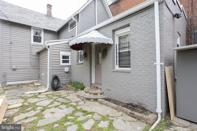 rear view of house with brick siding and a chimney