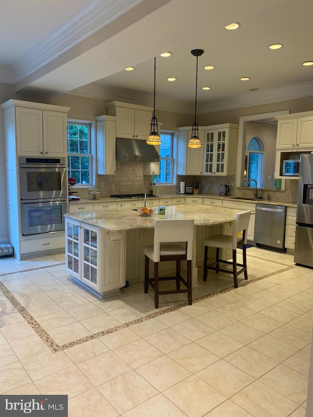 kitchen with ornamental molding, under cabinet range hood, backsplash, and appliances with stainless steel finishes