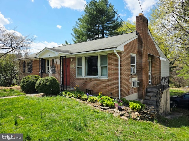 view of front facade with a chimney, a front yard, and brick siding