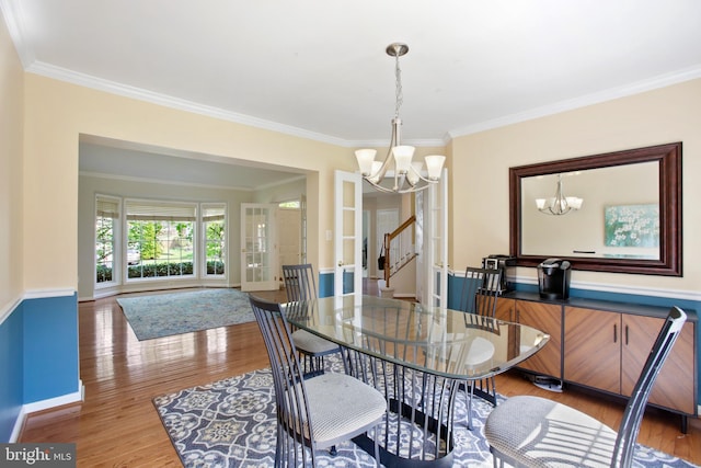 dining area with an inviting chandelier, ornamental molding, and wood finished floors