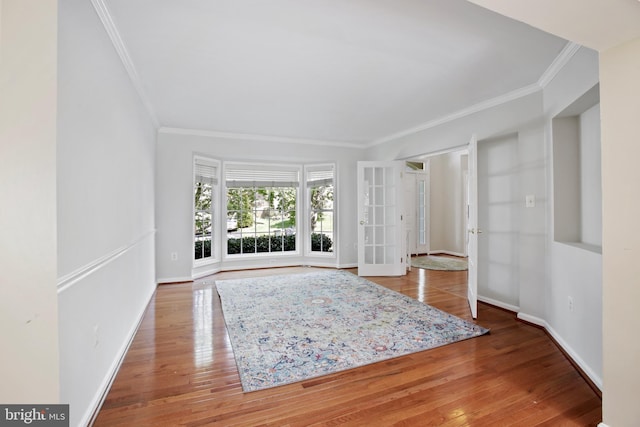 foyer entrance featuring wood-type flooring, ornamental molding, baseboards, and french doors