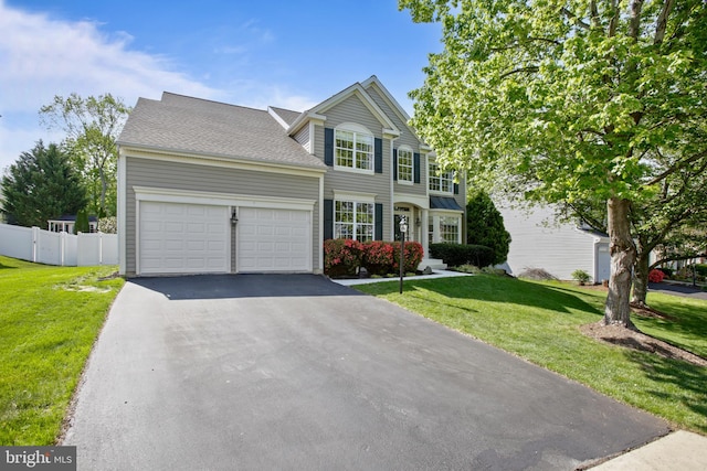 view of front of home with an attached garage, fence, a front yard, and aphalt driveway