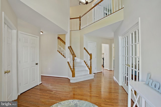entryway featuring baseboards, stairs, wood finished floors, and a towering ceiling