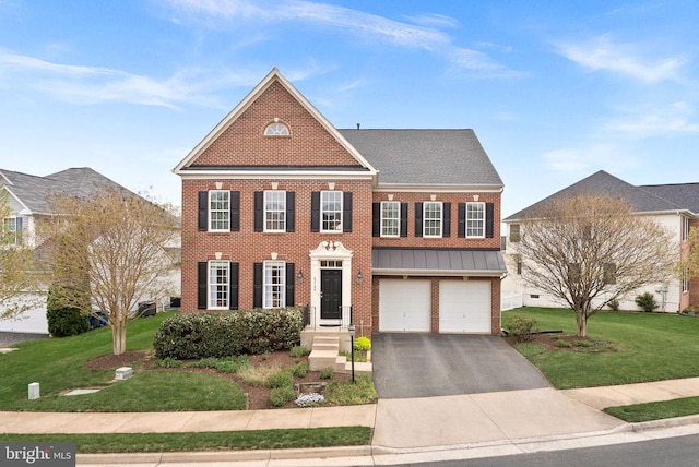 view of front of house with a standing seam roof, driveway, a front yard, brick siding, and an attached garage
