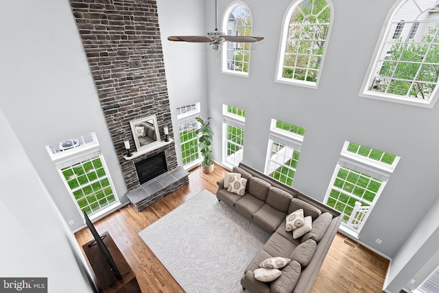 living area featuring visible vents, a high ceiling, ceiling fan, and wood finished floors
