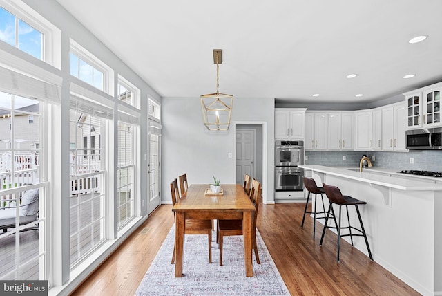 dining area with light wood-style floors, recessed lighting, and a chandelier