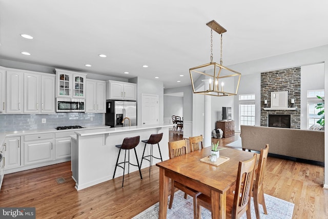 dining room featuring recessed lighting, an inviting chandelier, light wood finished floors, and a fireplace