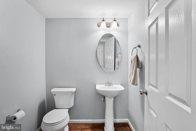 bathroom featuring toilet, baseboards, a sink, and wood finished floors
