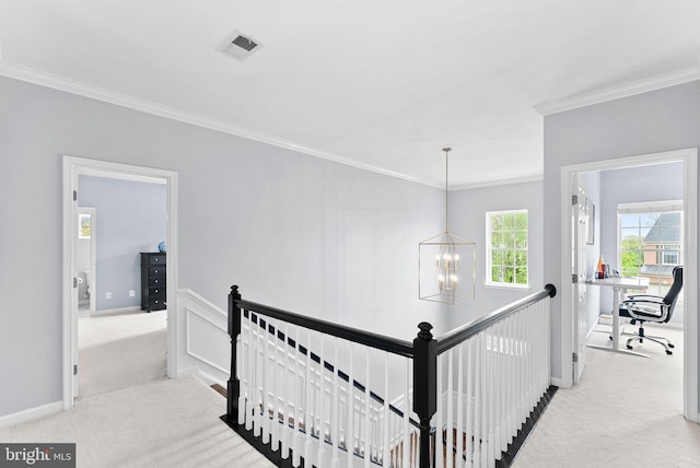 hall featuring crown molding, carpet flooring, a chandelier, and an upstairs landing