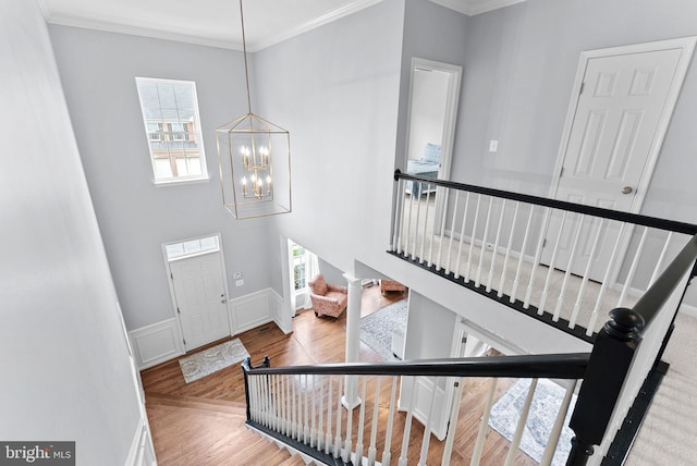 foyer entrance with crown molding, stairs, wood finished floors, and a chandelier
