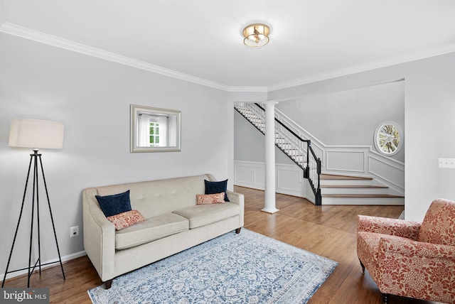 living area with crown molding, decorative columns, stairs, and wood finished floors