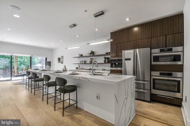2515 Ontario Rd NW Unit 1, Washington, DC 20009 - kitchen featuring appliances with stainless steel finishes, modern cabinets, a sink, open shelves, and a large island with sink