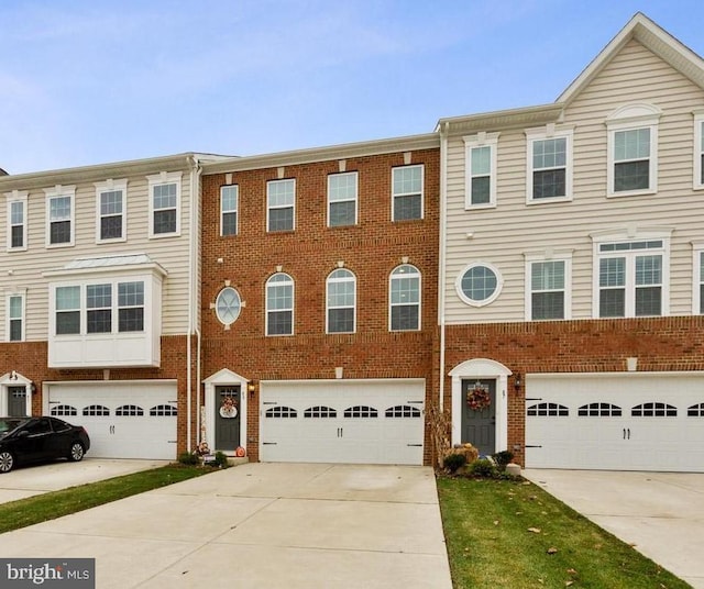 townhome / multi-family property featuring brick siding, an attached garage, and driveway