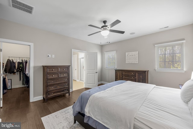 bedroom with visible vents, dark wood-style flooring, baseboards, and a spacious closet