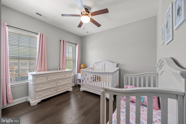 bedroom featuring visible vents, baseboards, dark wood-type flooring, and a nursery area
