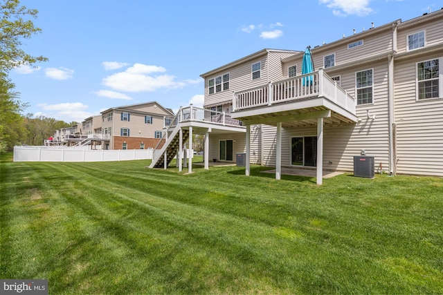 back of property with a lawn, fence, a wooden deck, and central AC unit