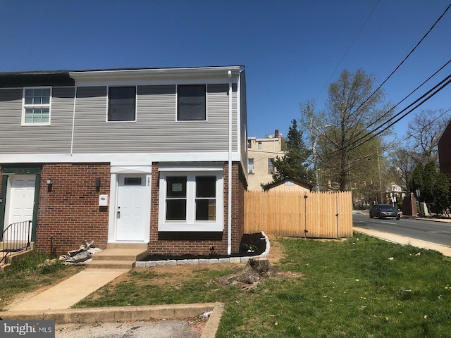 view of front of property featuring brick siding, a front lawn, and fence