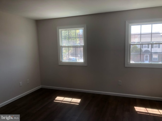 empty room with baseboards and dark wood-style floors