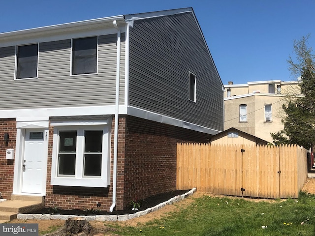 view of home's exterior featuring fence and brick siding