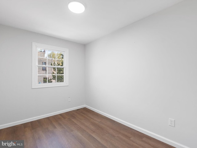 unfurnished room featuring baseboards and dark wood-style floors