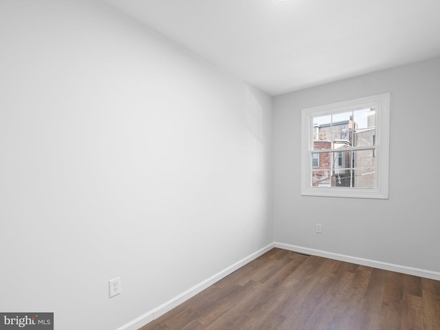 empty room with baseboards and dark wood-style floors