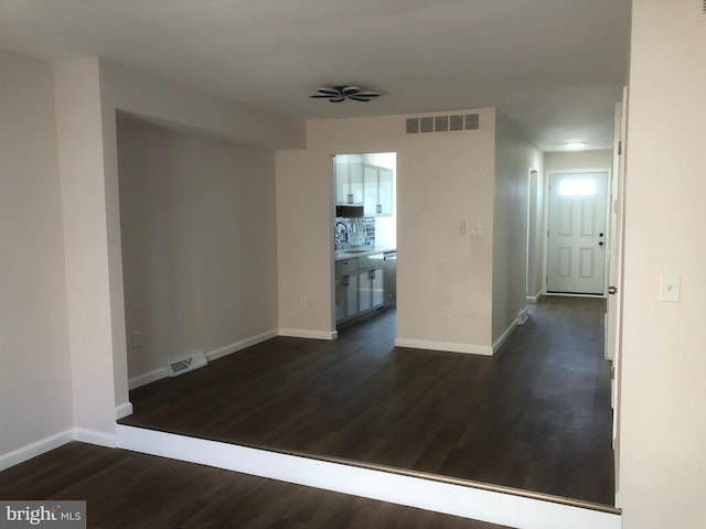 interior space featuring baseboards, visible vents, and dark wood-style floors