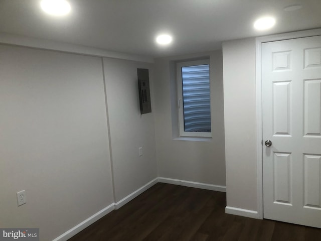 basement with electric panel, baseboards, and dark wood-style flooring
