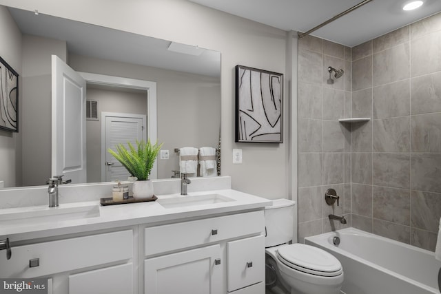 full bathroom with a sink, toilet, double vanity, and shower / washtub combination