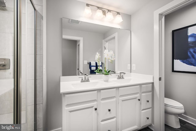 full bathroom featuring visible vents, toilet, a sink, double vanity, and baseboards