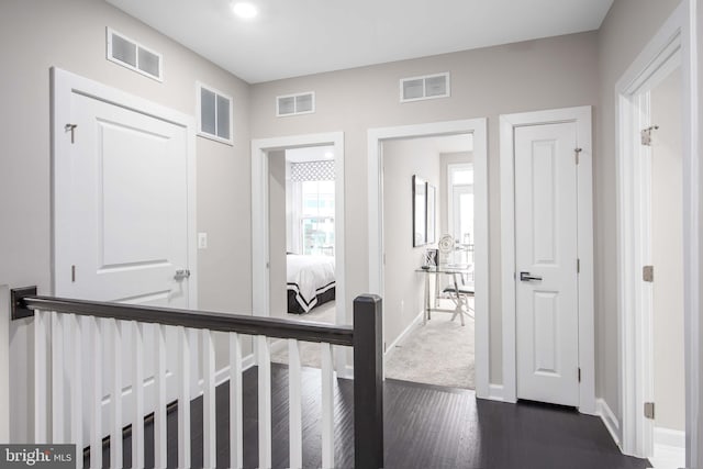 hallway with baseboards, dark wood-style floors, and visible vents