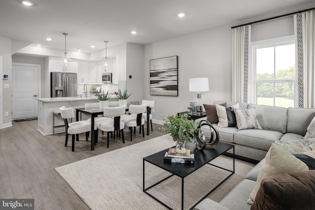 living room featuring recessed lighting, light wood-type flooring, and baseboards