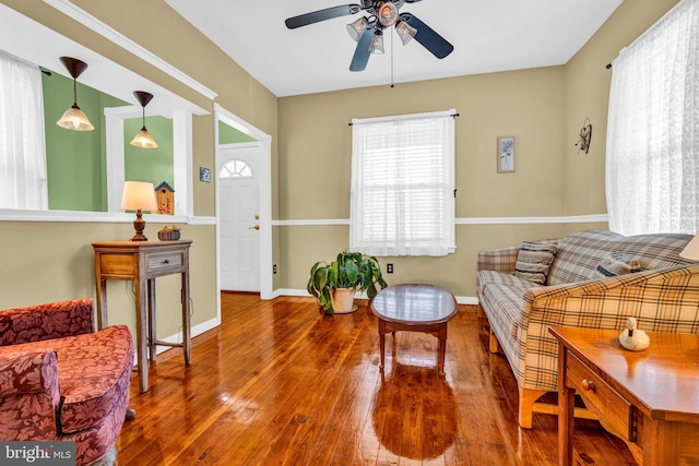 living room with baseboards, a ceiling fan, and hardwood / wood-style flooring