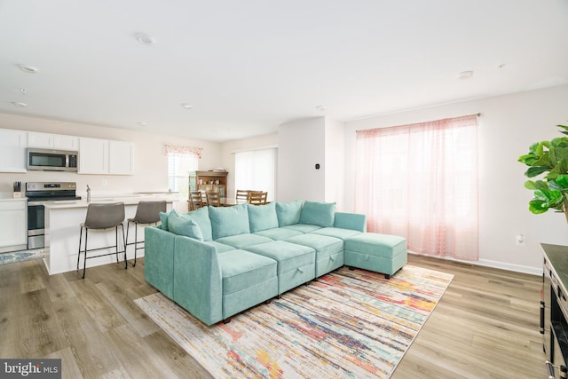 living room with recessed lighting, light wood finished floors, and baseboards