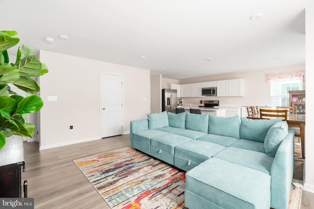 living room featuring recessed lighting, light wood-type flooring, and baseboards