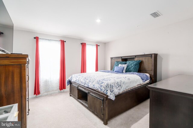 bedroom with baseboards, visible vents, and light colored carpet
