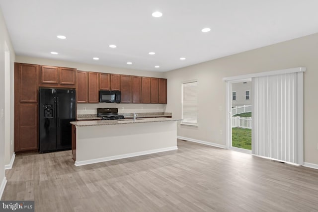 kitchen with light wood-style flooring, baseboards, and black appliances