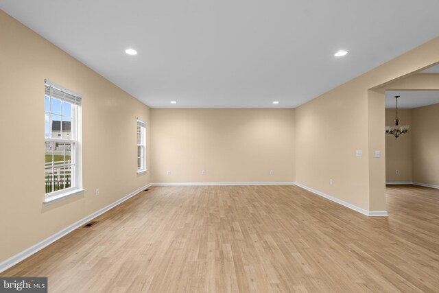 unfurnished room featuring visible vents, baseboards, a notable chandelier, light wood-type flooring, and recessed lighting