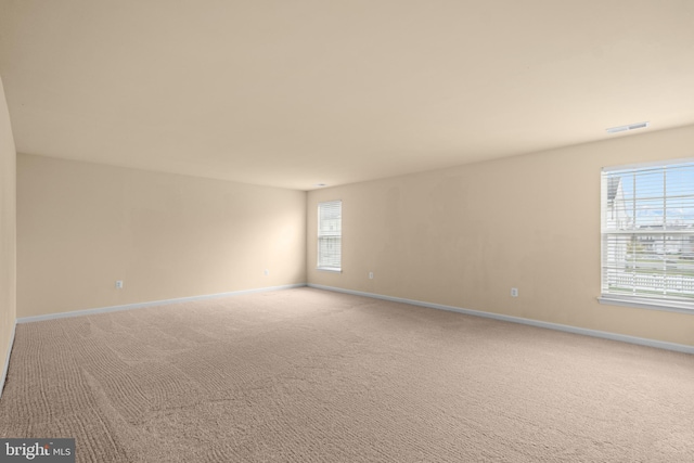 unfurnished room with visible vents, baseboards, and light carpet