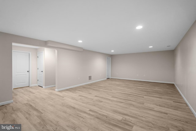 finished below grade area featuring light wood-style flooring, baseboards, visible vents, and recessed lighting