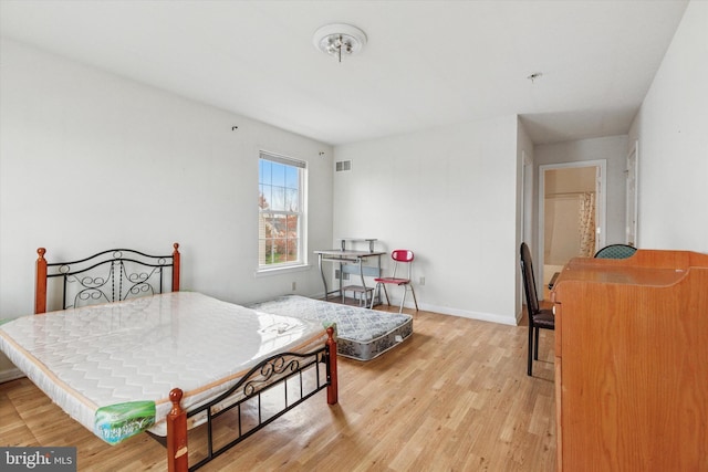 bedroom featuring light wood finished floors, baseboards, and visible vents