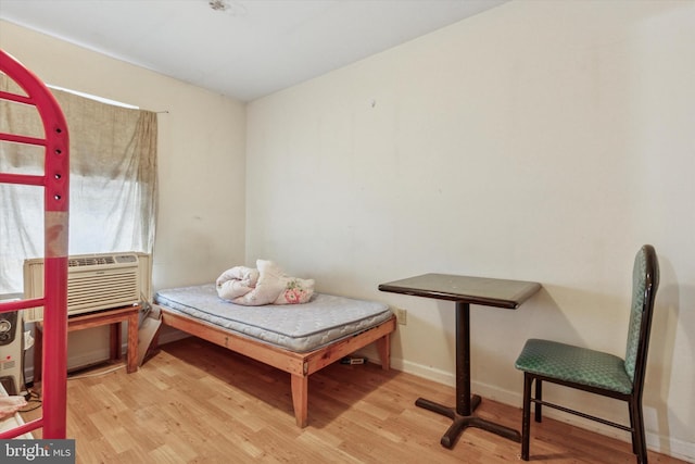 bedroom with cooling unit, wood finished floors, and baseboards