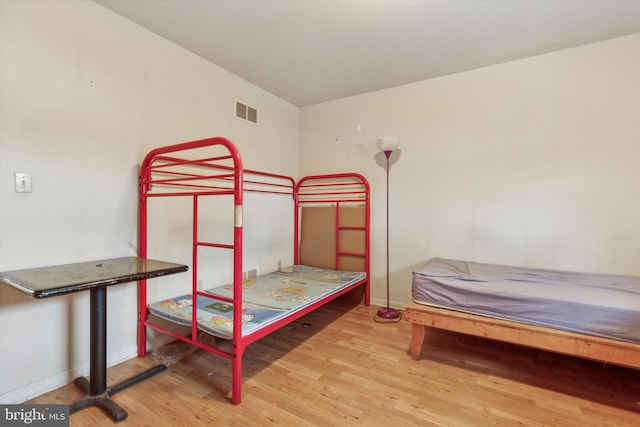 bedroom with wood finished floors, baseboards, and visible vents