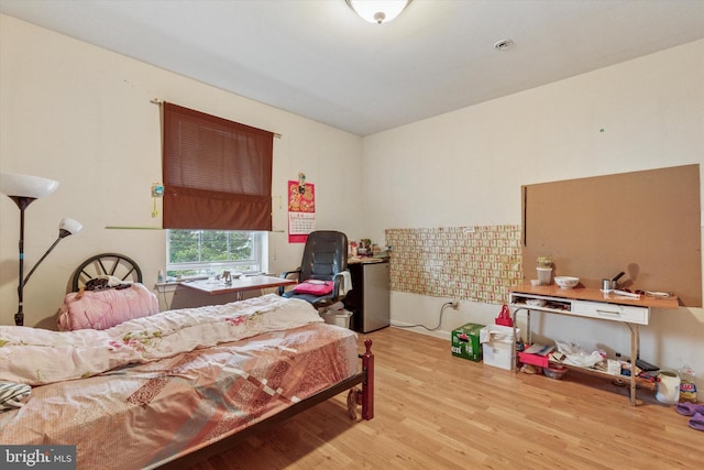 bedroom with wood finished floors and fridge